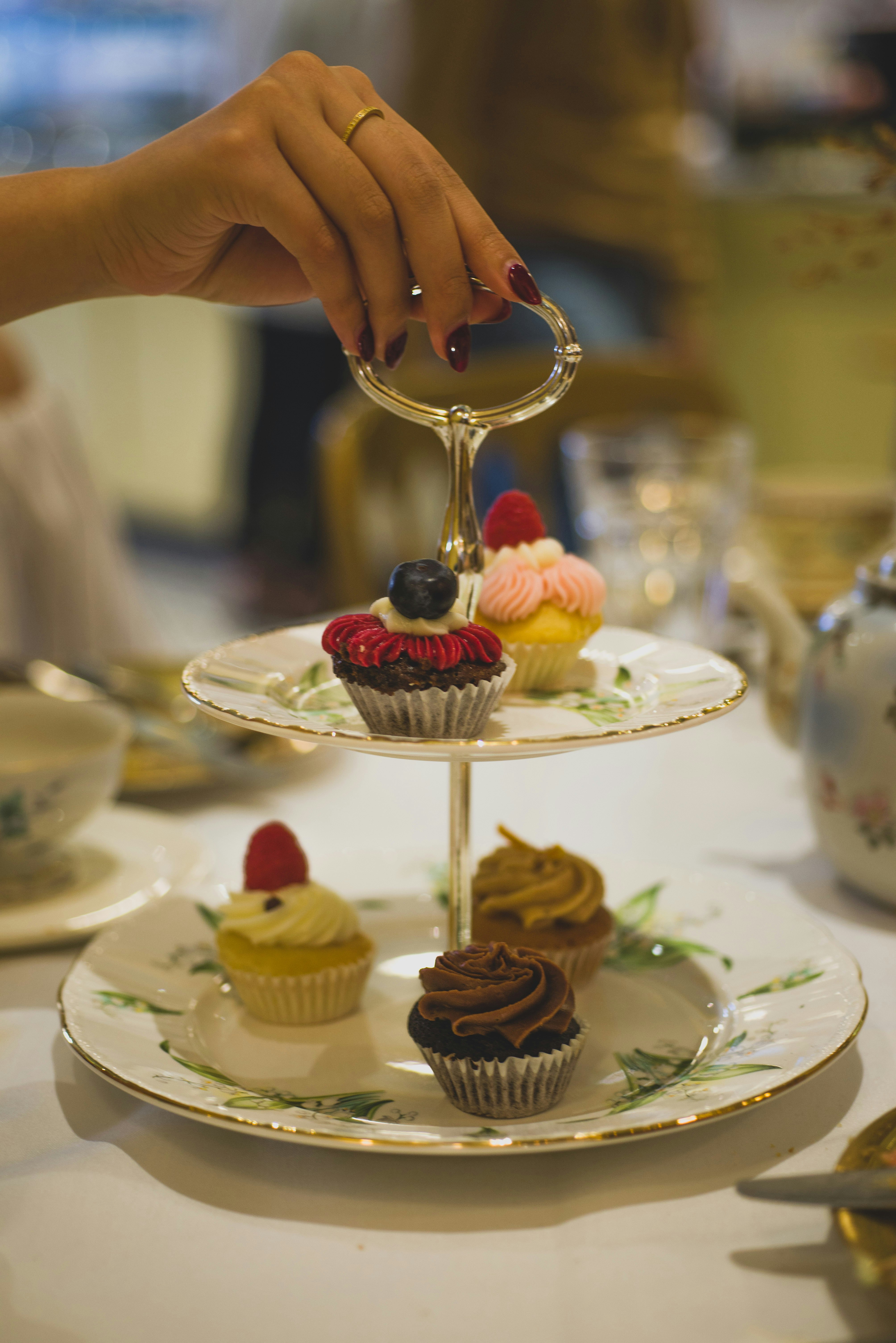 person holding stainless steel fork with white icing on top of white cake